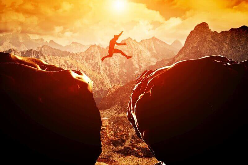 A man jumping from one rock to the other